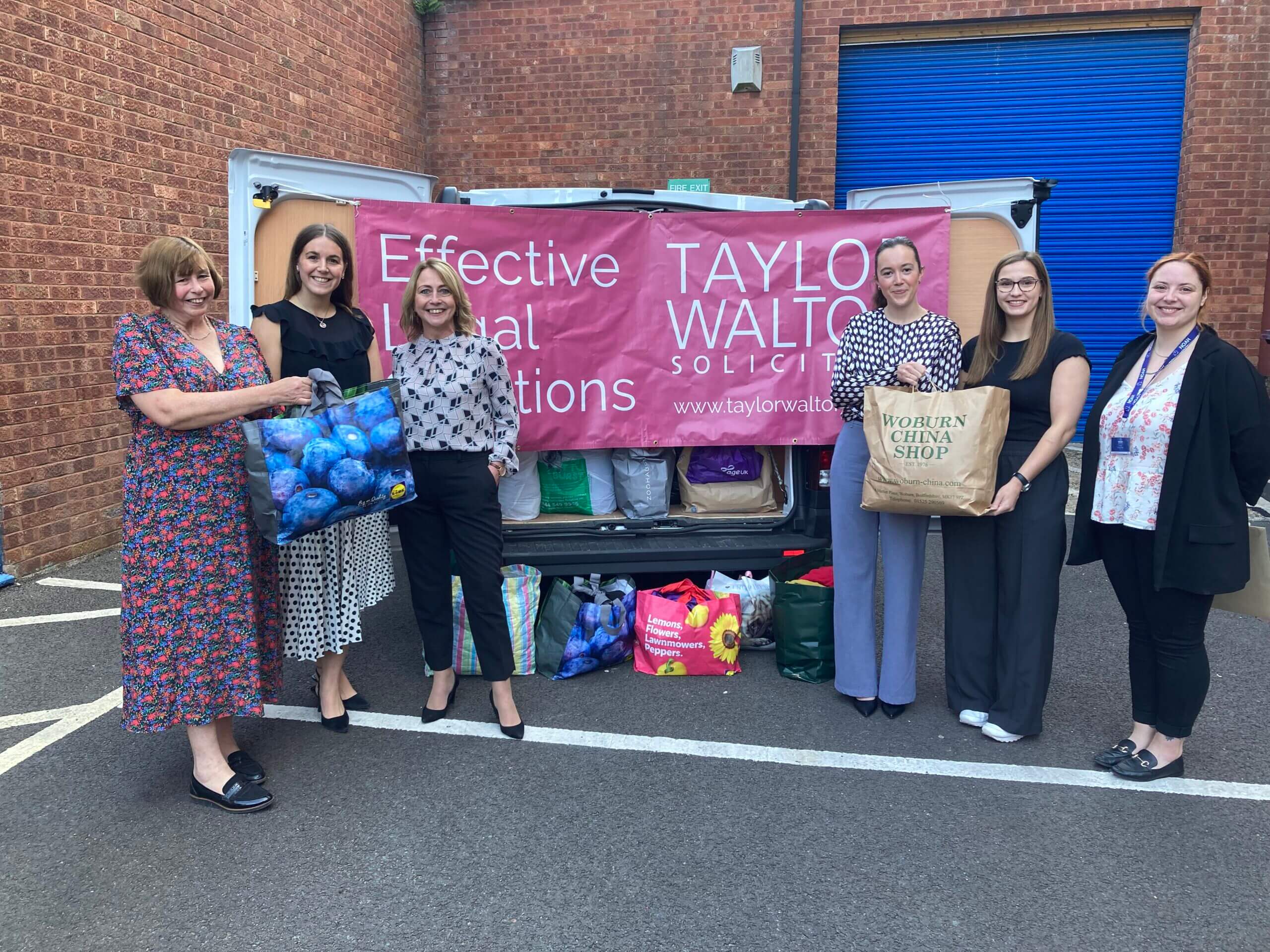 Team members standing in front of a car boot full of bags of clothes